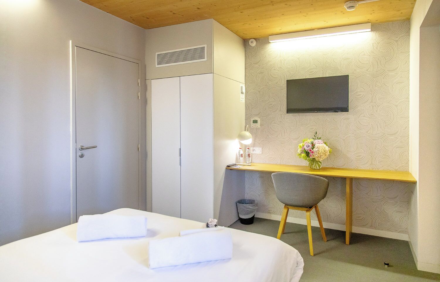 Ein Hotelzimmer mit Bett, Schreibtisch, Stuhl, Fernseher und Mülleimer.