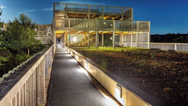 Un edificio moderno con una galería techada que conduce a una estructura de varios niveles.