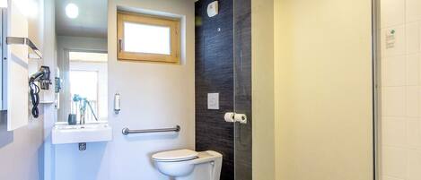 Un baño moderno con cabina de ducha de vidrio, inodoro y lavabo con espejo superior.