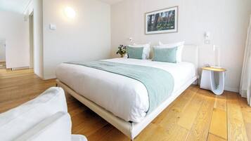 Un dormitorio moderno con una cama grande, una mesita de noche, un cuadro en la pared y suelo de madera.