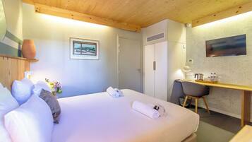 Habitación de hotel con cama, escritorio, silla, televisión y ventana con vistas.