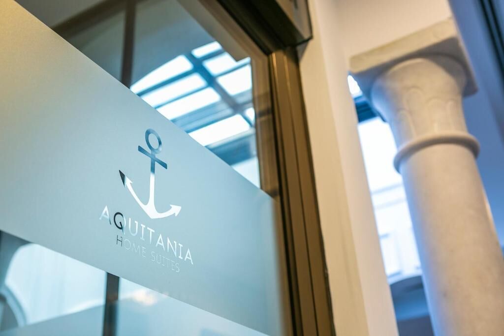 A sign with the text "AQUITANIA HOME SUITES" and an anchor symbol.