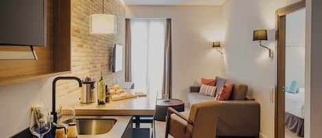 A modern kitchen with a brick wall, a dining area with a sofa, and a view of the outdoors.