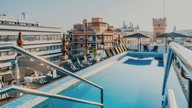 A rooftop pool with lounge chairs and a view of the cityscape.