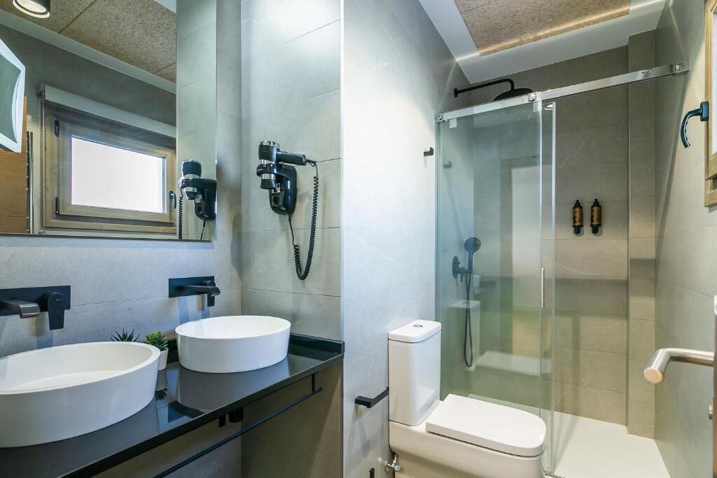 Une salle de bain moderne avec deux vasques rondes, une douche à l’italienne en verre et des toilettes.