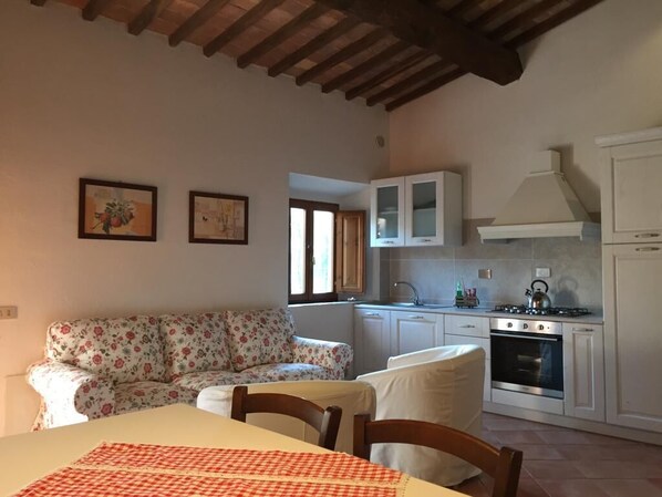 Una cucina compatta con mobili bianchi, un fornello a gas e una finestra.