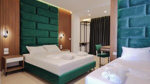 A hotel room with a large bed, a smaller bed, a desk, and a chair.