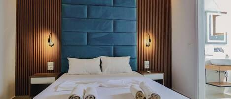 A modern hotel room with a large bed, wooden paneling, and a blue headboard.