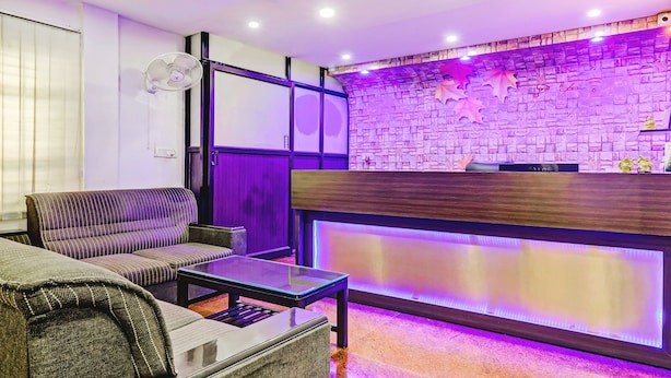 Zona de recepción con pared de piedra, mostrador de recepción y asientos con mesa de vidrio.