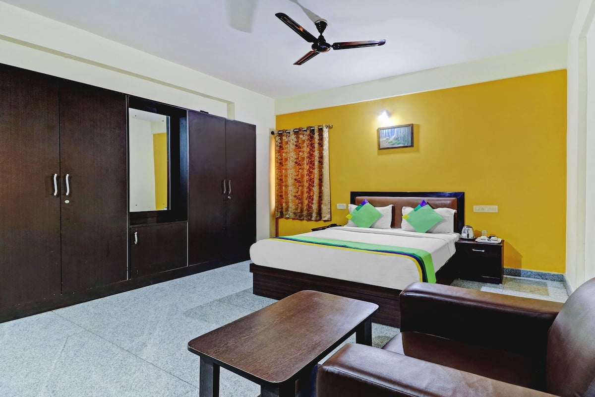 A hotel room with a bed, a desk, a chair, a wardrobe, and a ceiling fan.