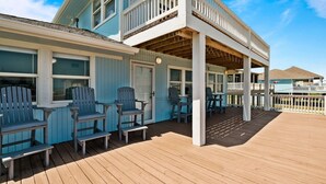 Un bâtiment à deux étages doté d’une terrasse en bois et d’un espace extérieur aménagé pour s’asseoir.