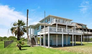 A two-story beachfront house with a balcony, a covered porch, and a staircase leading to the upper level. - BOLIVAR DEL MAR - 2nd row, great views, fenced yard, 3 bedroom. (Crystal Beach)