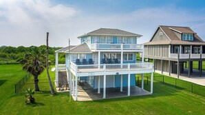 Une maison à deux étages située en bord de mer, dotée d’un balcon, d’une terrasse couverte et d’une cour clôturée.