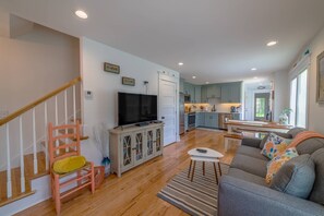 A living room with a sofa, a TV, and a staircase.