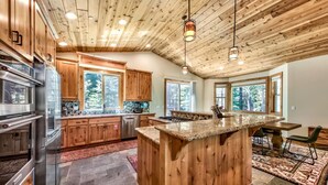 Une cuisine moderne avec des meubles en bois, un plan de travail en granit et un grand îlot central.