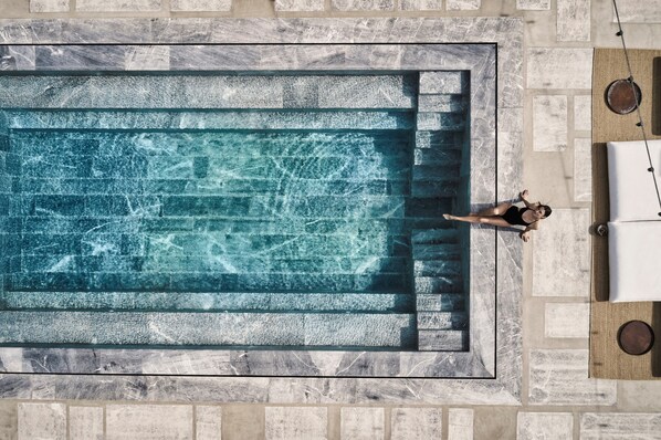 Vista aérea de una piscina rectangular con agua cristalina, rodeada de baldosas de piedra.