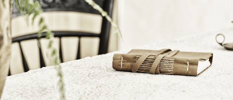 A rolled-up book on a textured table with a chair in the background.