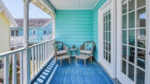 A blue porch with two wicker chairs and a small table, overlooking a residential area. - Renovated 3 BR, 2 BA w/Marsh Views & Short Walk to Beach (Garden City Beach)