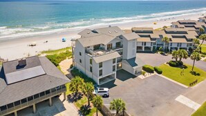 A coastal hotel with multiple buildings, a parking area, and a beach view. - Penthouse Oceanfront Villa at Inlet Point on Litchfield Beach (Pawleys Island)