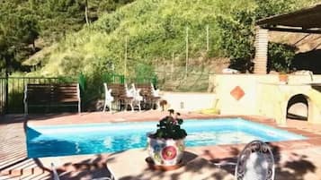 Relax by the serene pool surrounded by lush greenery and a stone wall.