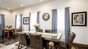 Un comedor con una mesa redonda, sillas de cuero, cortinas estampadas y un reloj en la pared.
