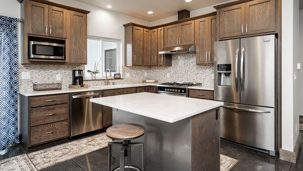 Una cocina moderna con armarios de madera, electrodomésticos de acero inoxidable y una isla central.