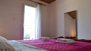 A bedroom with a bed, a window with curtains, a mirror, and a chair. - Apartment Tommy (Malinska-Dubasnica)