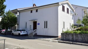 A white building with a small entrance, a staircase, and a stone wall. - Apartment Tommy (Malinska-Dubasnica)