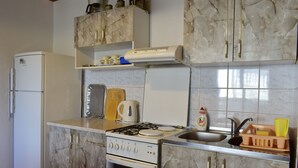 A kitchen with a refrigerator, stove, sink, and marble cabinets. - Apartment Tommy (Malinska-Dubasnica)
