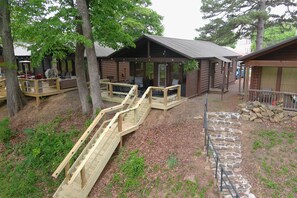 A log cabin with outdoor seating, a wooden deck, and a stone staircase.