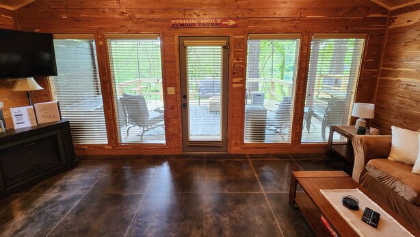 Una cabaña con interior de madera, televisor, sofá, mesa de centro y un letrero que indica el camino al lugar de pesca.