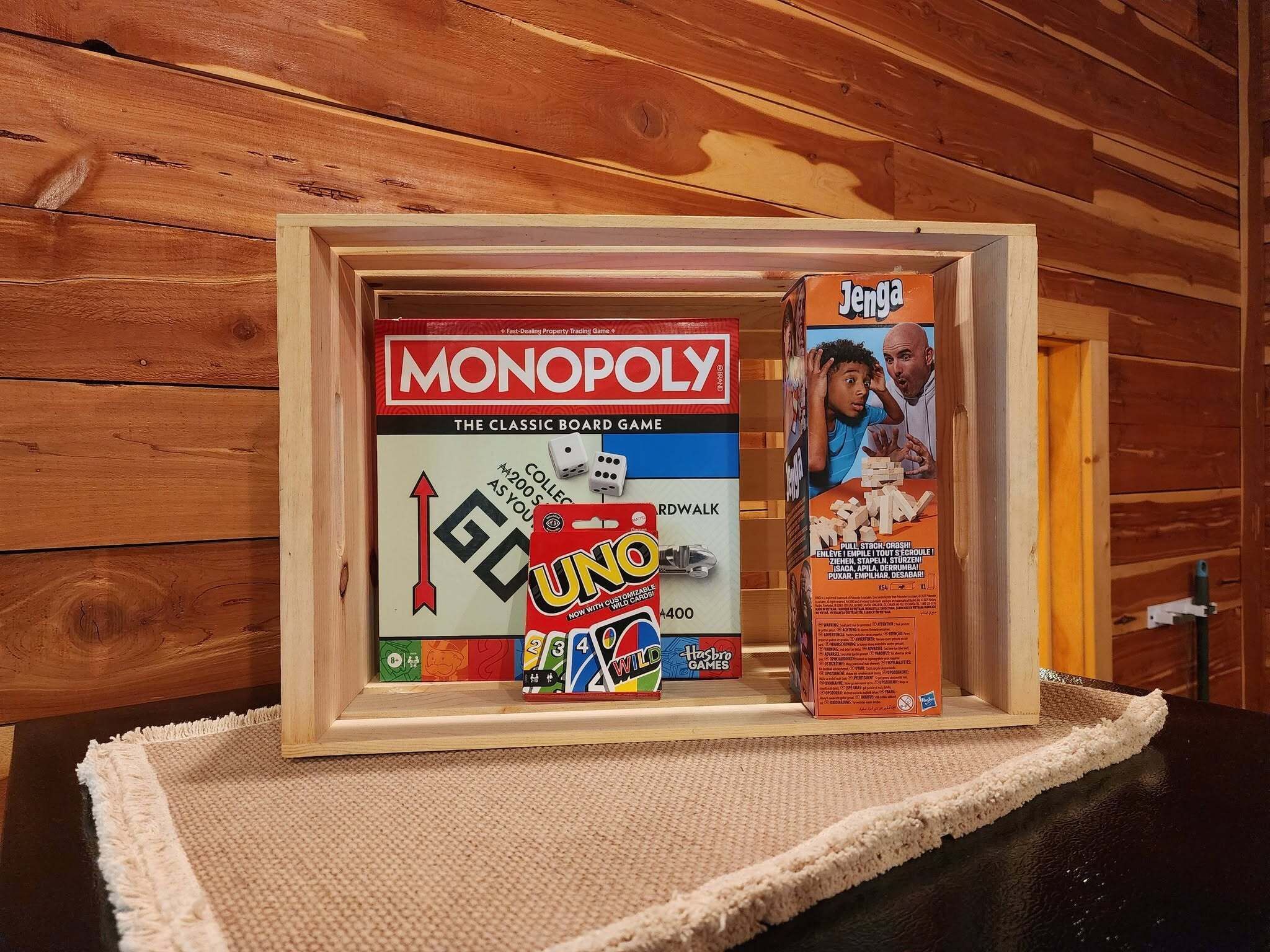 Une vitrine en bois contenant un jeu de société Monopoly et une boîte de cartes UNO.