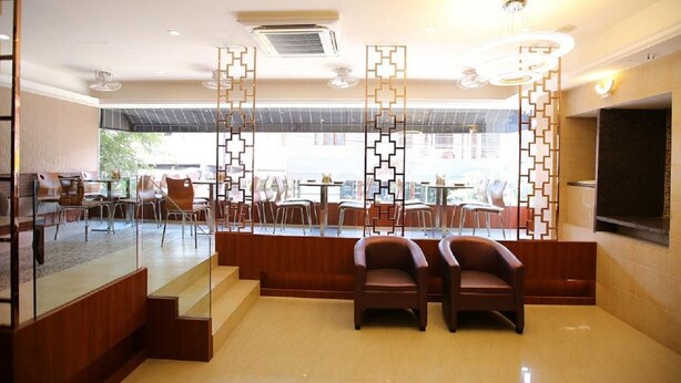 A modern lobby with a seating area, a staircase, and a view of the outdoor area. - Hotel Venition Inn (Coimbatore)