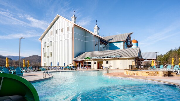 A large building with a swimming pool, outdoor seating, and a distinctive blue and orange roof. - The Lodge at Camp Margaritaville (Pigeon Forge)