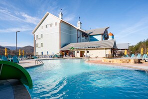 A large building with a swimming pool, outdoor seating, and a distinctive blue and orange roof. - The Lodge at Camp Margaritaville (Pigeon Forge)