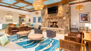 A spacious lobby with a stone fireplace, comfortable seating, and a high ceiling with wooden beams. - The Lodge at Camp Margaritaville (Pigeon Forge)