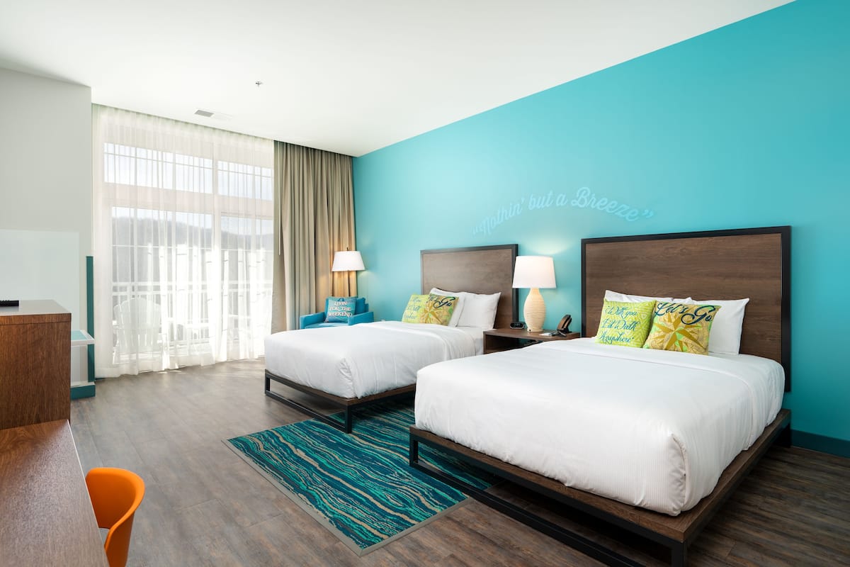 A hotel room with two beds, a desk, and a chair.