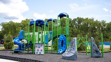 Ein Spielplatz mit einer blauen Rutsche, Klettergerüsten und einer Kletterwand.
