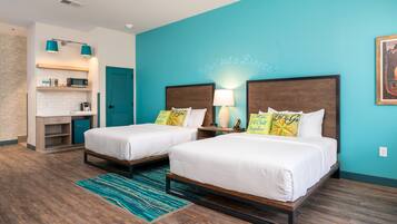 A hotel room with two beds, a kitchenette, and a bathroom.