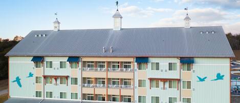 A multi-story hotel with a flat roof, multiple balconies, and a distinctive bird mural on the facade.