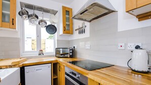 A modern kitchen with wooden cabinets, a built-in oven, a microwave, and a kettle.