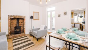 A living room with a brick fireplace, a grey armchair, and a dining area set for a meal.