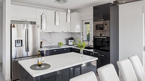 A modern kitchen with a central island, stainless steel appliances, and white cabinetry. - Villa Stanka - 4 Bedrooms, 4 Bathrooms, gym, game room, pool with Whirlpool (Kastel Sucurac)
