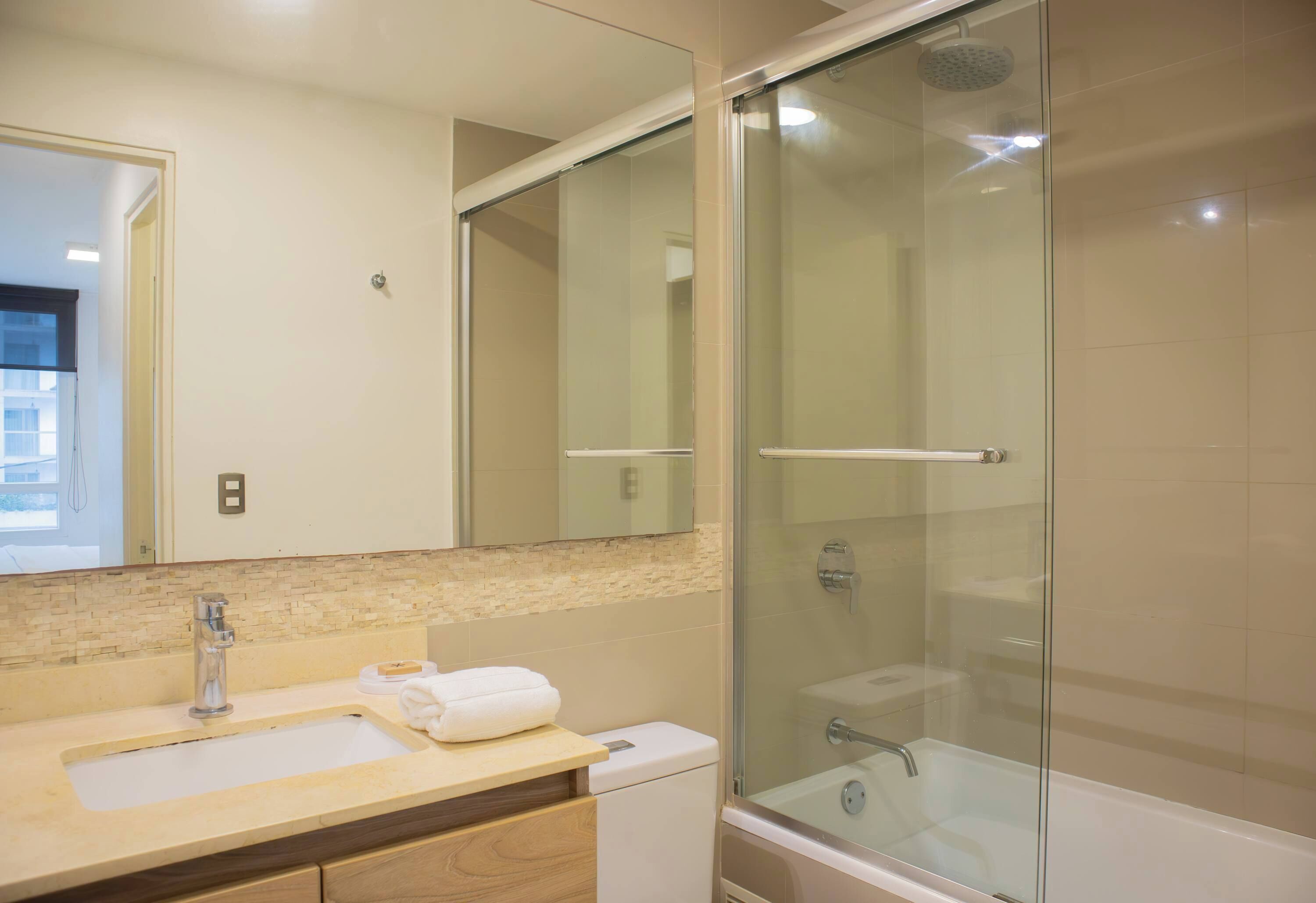 A bathroom with a glass-enclosed shower, a sink with a mirror, and a toilet.
