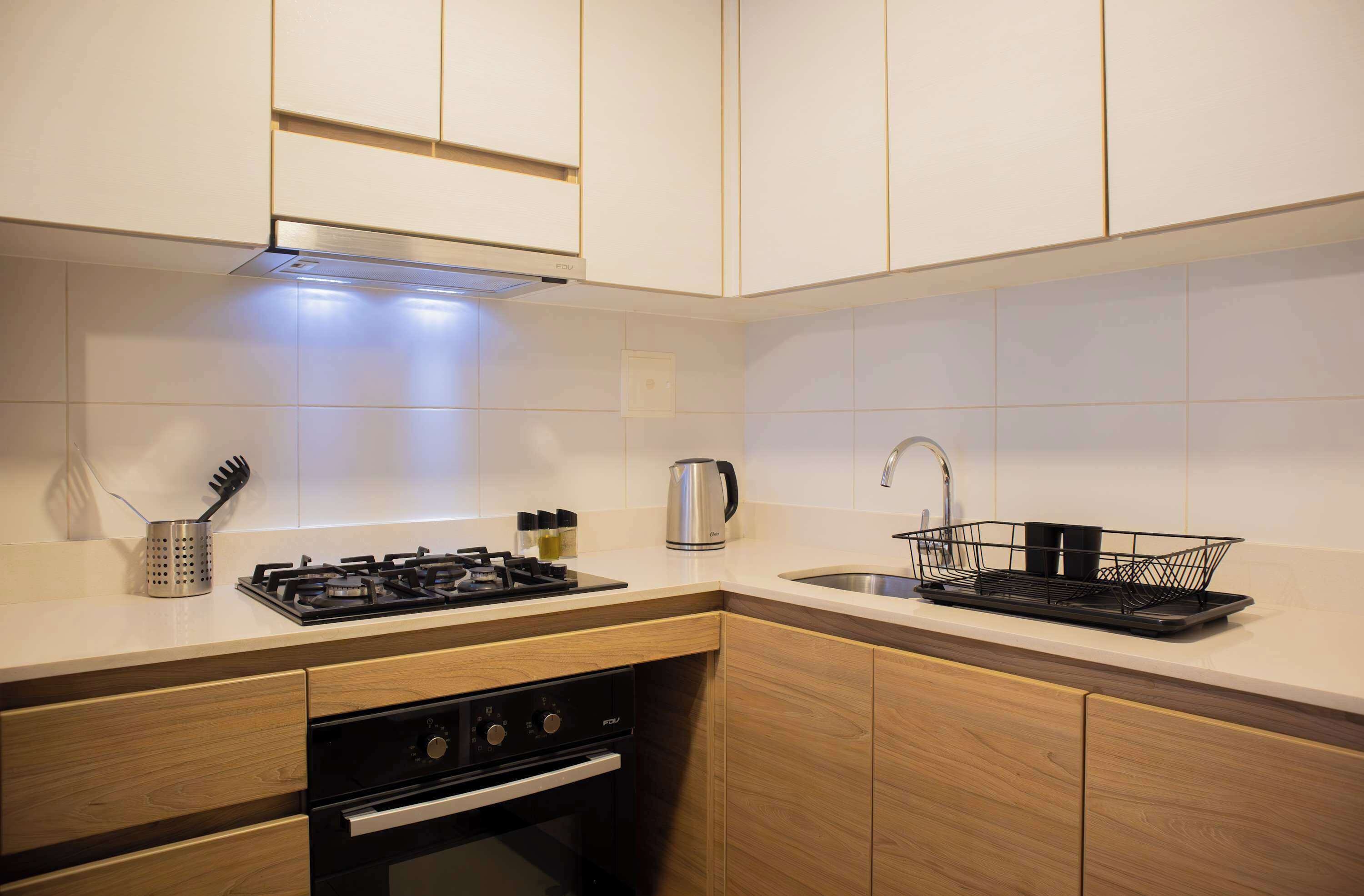 Une cuisine moderne avec des meubles en bois, une cuisinière en acier inoxydable et un évier noir.