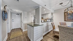 A modern kitchen with white cabinetry, a marble countertop, and a built-in island.