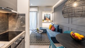 A modern kitchen with a black stove, a dining area with a round table, and a blue sofa. - Ports Crossroad E (Πειραιάς)