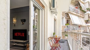 A balcony with a TV, outdoor furniture, and a railing. - Ports Crossroad E (Πειραιάς)