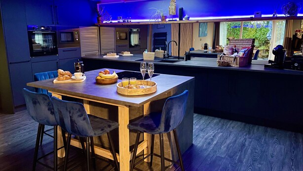 Una cocina moderna con una isla central, taburetes de bar y alimentos para el desayuno.