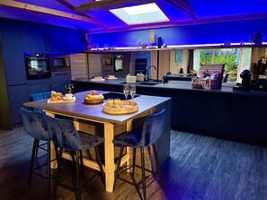 A modern kitchen with a central island, bar stools, and breakfast items. - Luxury lodge with hot tub at foot of South Downs, near beach Ferring West Sussex (Ferring)